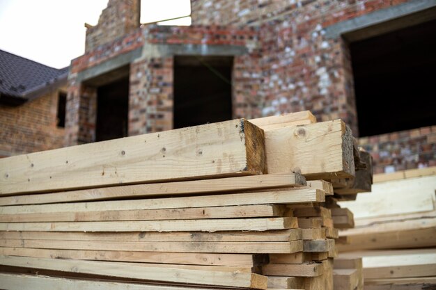 Primer plano de la pila apilada de tablas de madera rugosas irregulares de color marrón natural iluminadas por el sol brillante. Madera industrial para carpintería, construcción, reparación y mobiliario, material maderero para la construcción.