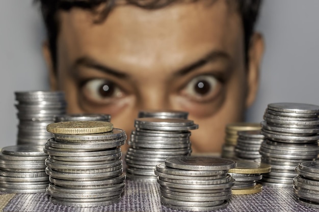 Foto primer plano de pilas de monedas en la mesa con un hombre mirando