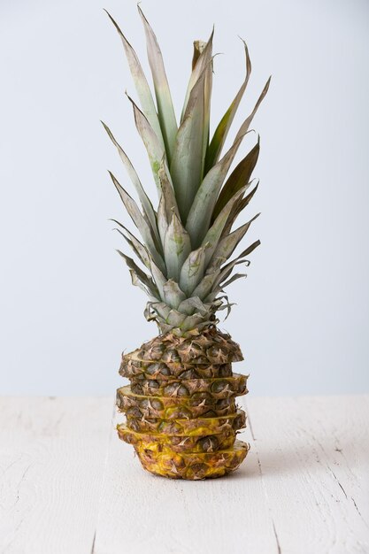 Primer plano de piña cortada en la mesa de madera blanca y sobre fondo azul claro