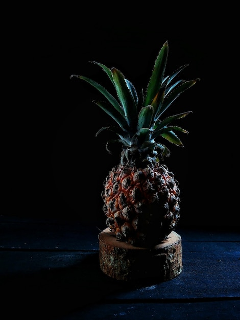 Primer plano de una piña en la mesa contra un fondo negro