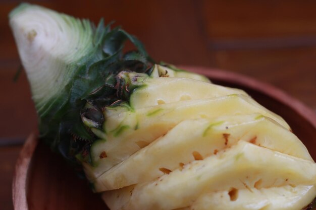 Foto un primer plano de una piña pelada en un concepto de foto de frutas de cuenco de madera