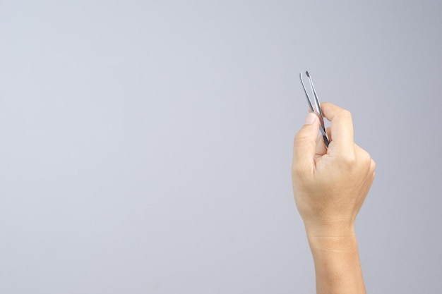 Primer plano de pinzas de mano contra un fondo gris