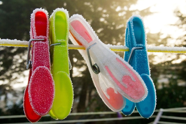 Foto primer plano de pinzas de ropa de varios colores colgando de una cuerda