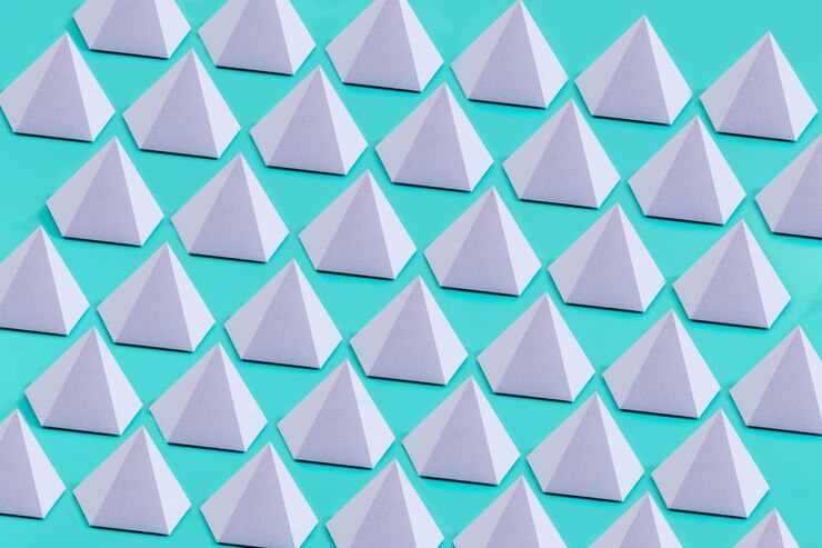 Foto primer plano de pirámides pentagonales de origami violeta en una superficie azul bajo las luces