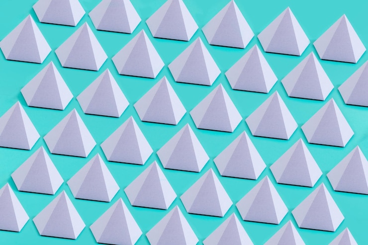 Foto primer plano de pirámides pentagonales de origami violeta en una superficie azul bajo las luces