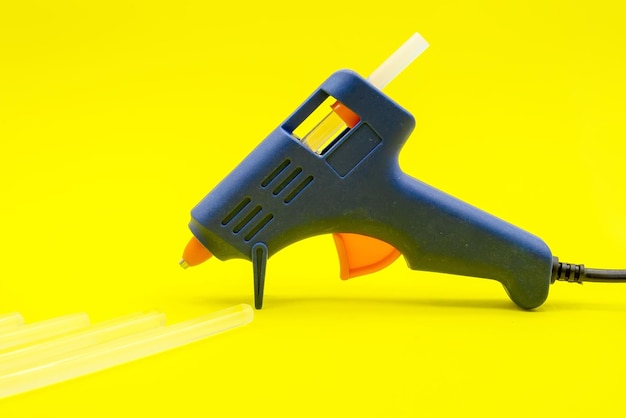 Primer plano de pistola de pegamento azul sobre un fondo amarillo