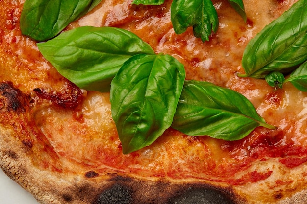 Primer plano de una pizza margherita con queso, tomates y hojas de albahaca