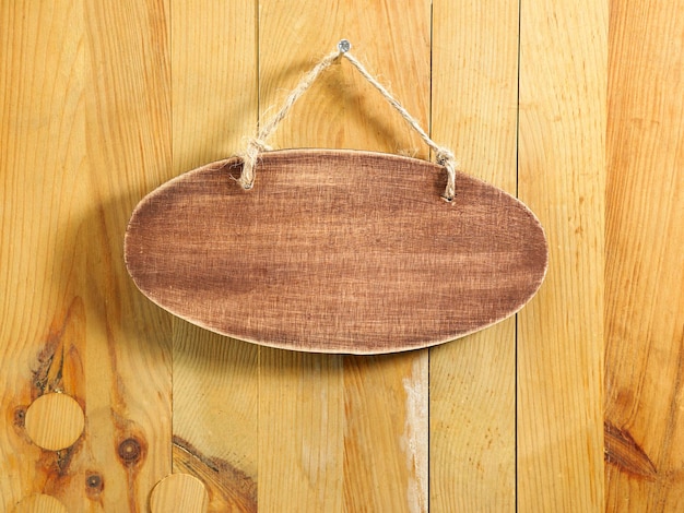 Primer plano de una placa de identificación vacía colgada en una puerta de madera