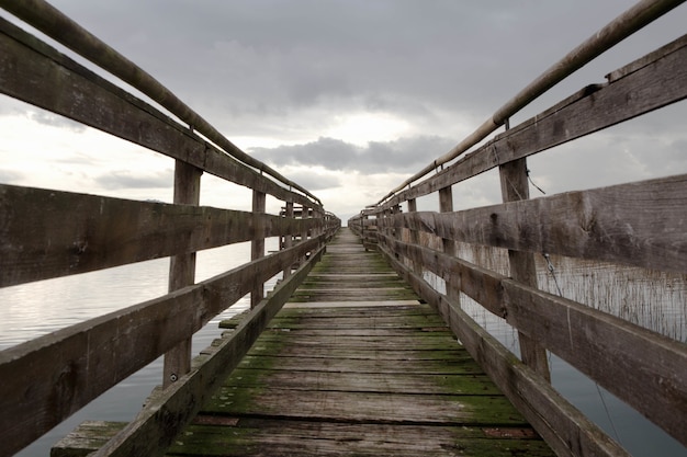 Foto primer plano de una plataforma de madera sobre el mar con cielo nublado