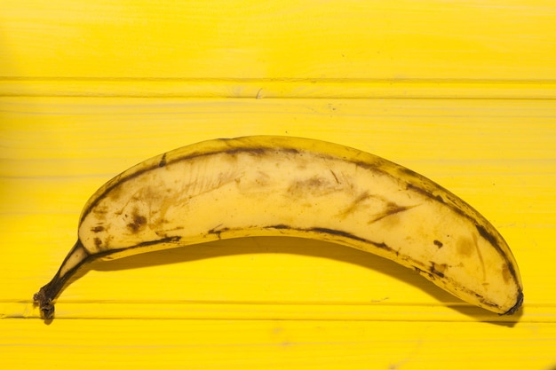 Primer plano de un plátano contra una superficie de madera amarilla