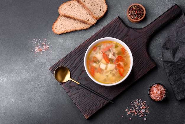 Primer plano de un plato de fideos con pollo y sopa de verduras en una mesa de hormigón