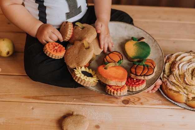 Primer plano de un plato con pan de jengibre cubierto con azúcar glas sobre el regazo del bebé. primer cumpleaños en un ambiente festivo. merienda saludable para niños. niño pequeño está sentado en la mesa de la cocina