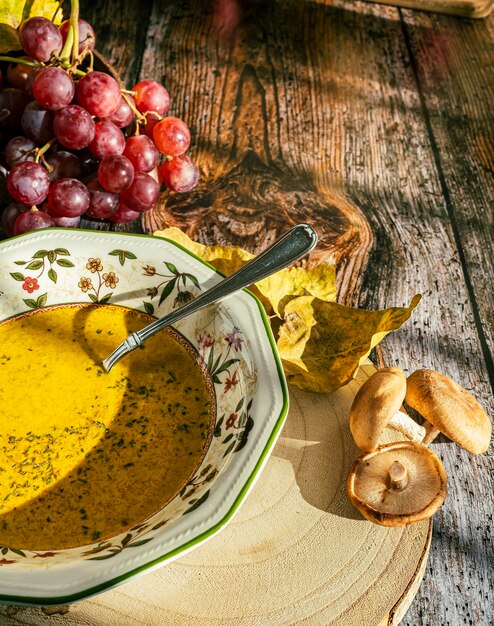 Primer plano de un plato con sopa de calabaza racimo de uvas decoran la imagen Fondo de madera