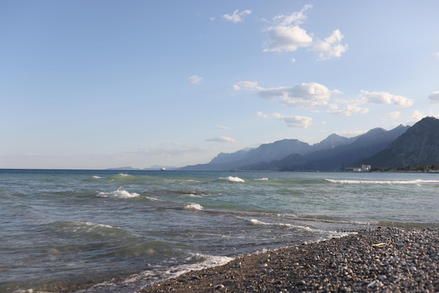 Primer plano de una playa de guijarros con fondo de cielo azul nublado paisaje de montaña pintoresca costa