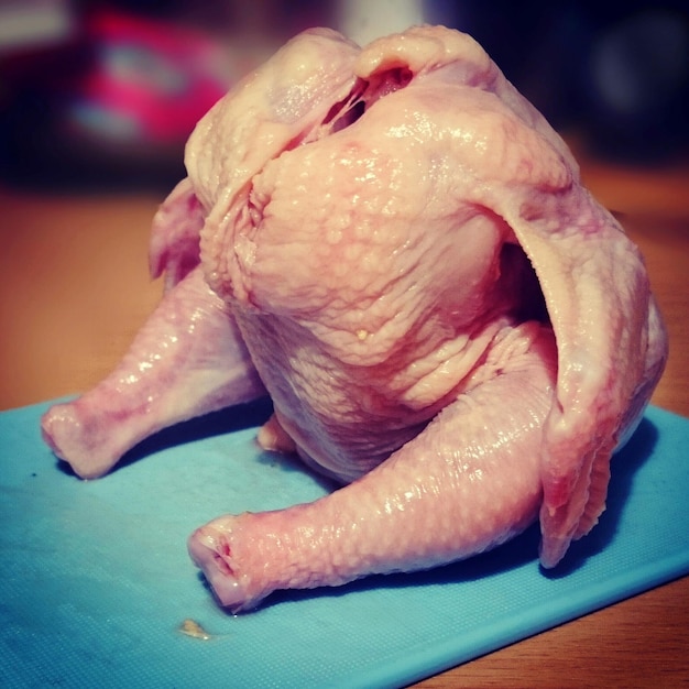 Foto primer plano de pollo crudo en la tabla de cortar en la mesa