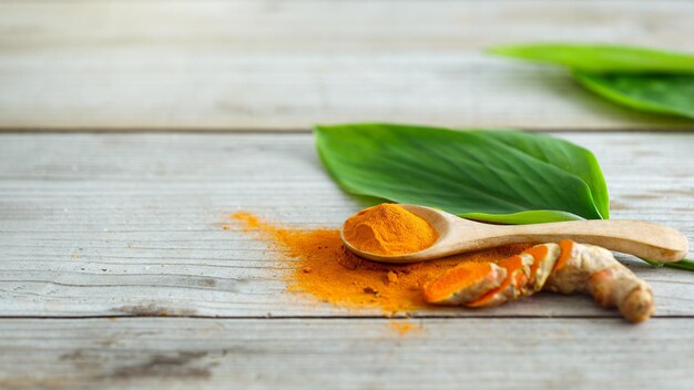 Foto primer plano de polvo de cúrcuma en el fondo de una mesa de madera