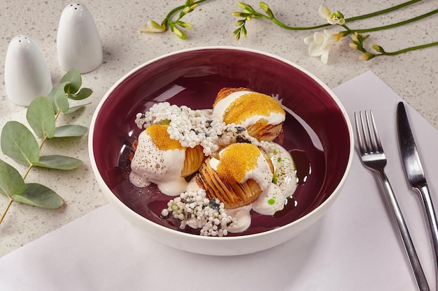 Primer plano de un postre gourmet dulce servido en un plato hondo con tenedor y cuchillo Elemento de menú delicioso Producto de pastelería decorado con flores Concepto de cocina de restaurante de vista superior