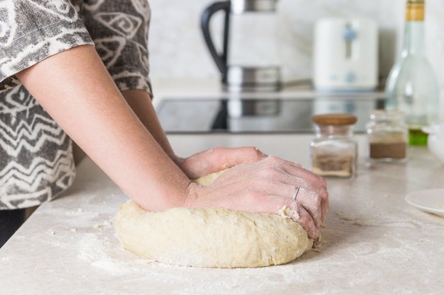 Primer plano de preparar y mezclar la masa. Manos femeninas amasar en la cocina moderna minimalista.