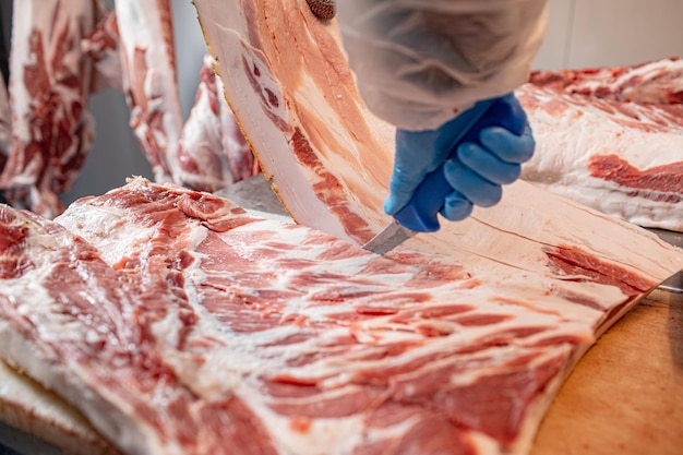 primer plano del procesamiento de carne en la industria alimentaria el trabajador corta el almacenamiento de cerdo crudo en el refrigerador