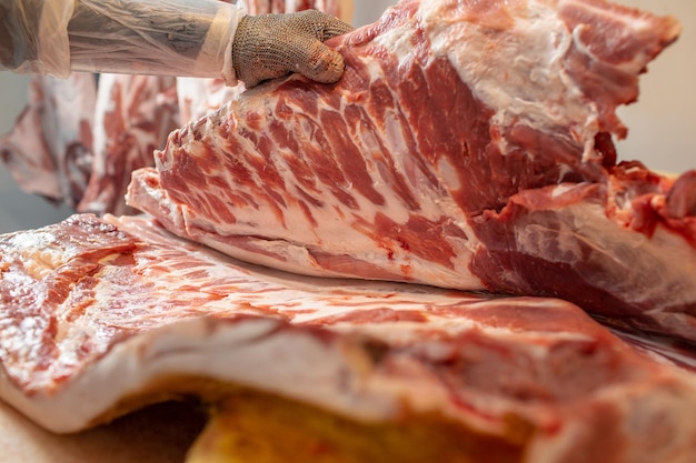 primer plano del procesamiento de carne en la industria alimentaria el trabajador corta el almacenamiento de cerdo crudo en el refrigerador