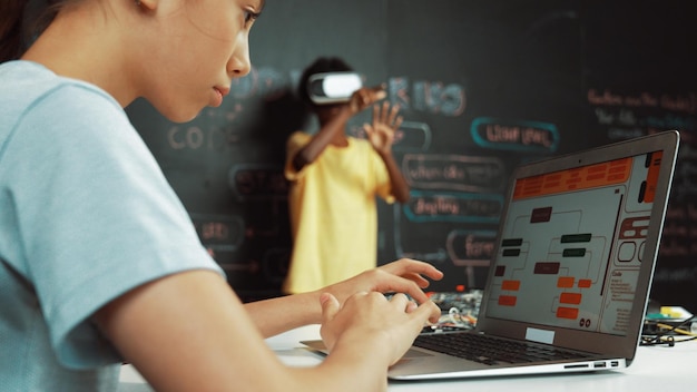 Primer plano del programa de codificación manual de la niña de la escuela mientras el estudiante usa la edificación VR