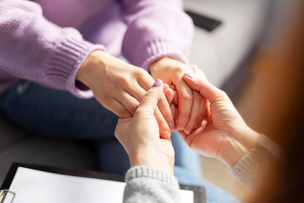 Primer plano de una psicóloga sosteniendo las manos de una mujer durante una sesión de terapia Psicoterapeuta apoyando a su paciente deprimido
