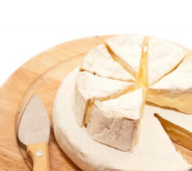 Foto primer plano de un queso con un cuchillo de cocina en una tabla de cortar sobre un fondo blanco