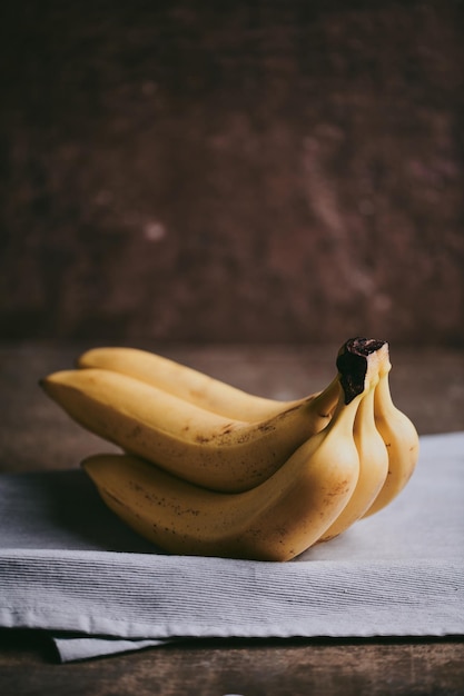 Foto primer plano de un racimo de plátanos sobre un fondo de tela oscura