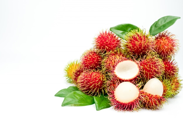 Primer plano de rambután maduro rojo fresco (Nephelium lappaceum) con hojas aisladas