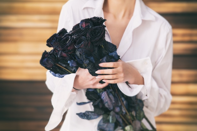 Primer plano de ramo de flores en manos de un modelo de niña sobre un fondo de madera