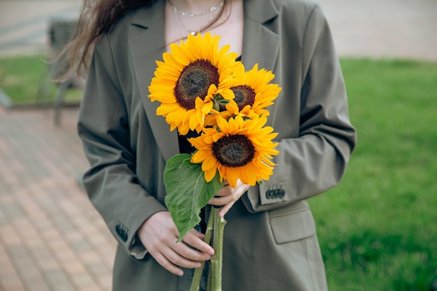 Primer plano un ramo de girasoles en manos femeninas sobre un fondo borroso