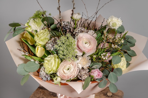 Primer plano de ramo de pequeñas flores rosadas en florero de vidrio con fondo gris borroso. Boda o cumpleaños, concepto de día de San Valentín.