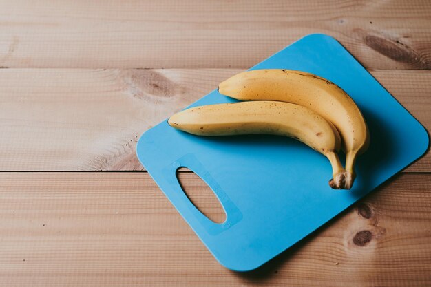 Un primer plano de un ramo de plátanos en el fondo de una mesa de cocina de madera