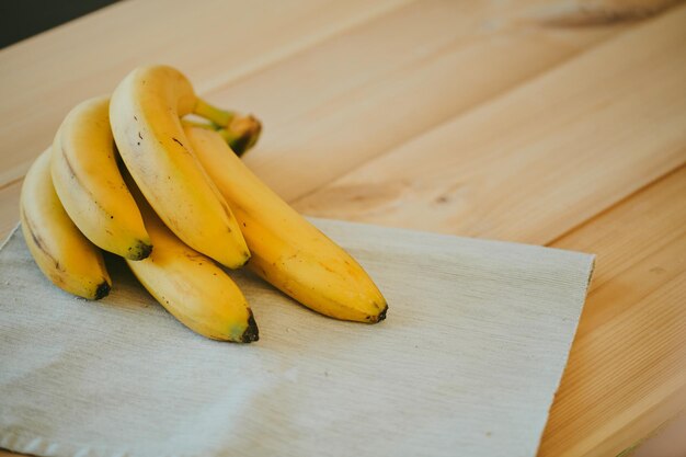 Un primer plano de un ramo de plátanos en el fondo de una mesa de cocina de madera