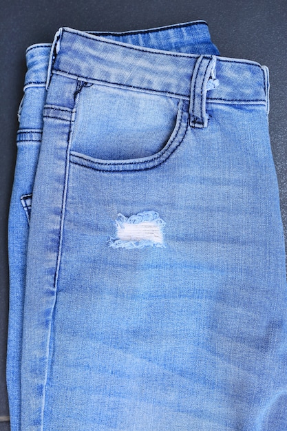 Primer plano rasgado en el fondo de los pantalones vaqueros azules. Textura de mezclilla con detalle