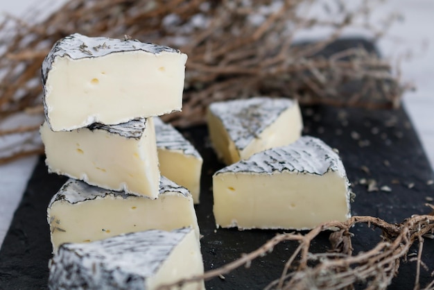 Primer plano de rebanadas de queso en medio de hierbas en la tabla de cortar en la cocina