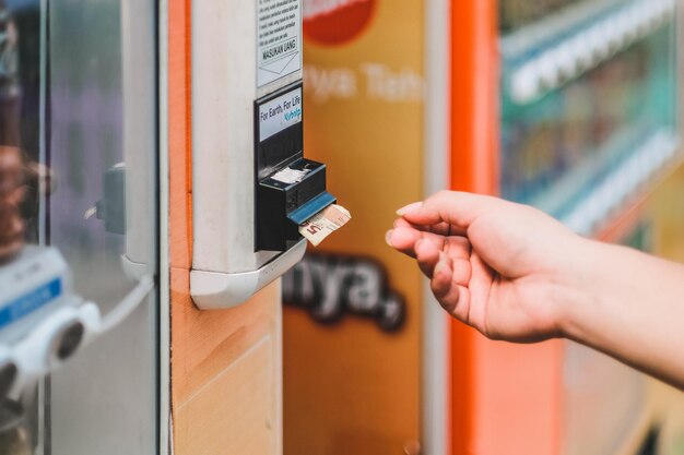 Primer plano de la recolección manual de papel moneda dispensado desde la máquina