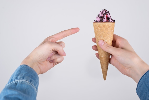 Foto primer plano recortado de la persona que ve la foto del delicioso helado de crema suave y el dedo demostrando venderlo aislado fondo gris