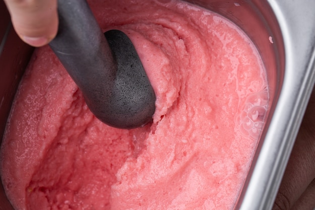 Primer plano de un refrescante desierto helado de baya dulce congelada en un recipiente con una cuchara