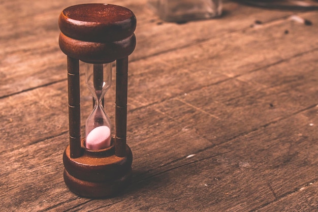 Foto primer plano de un reloj de arena en una mesa de madera