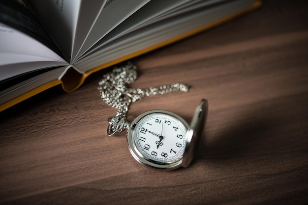 Foto un primer plano de un reloj de bolsillo dorado apoyado en una pila de libros