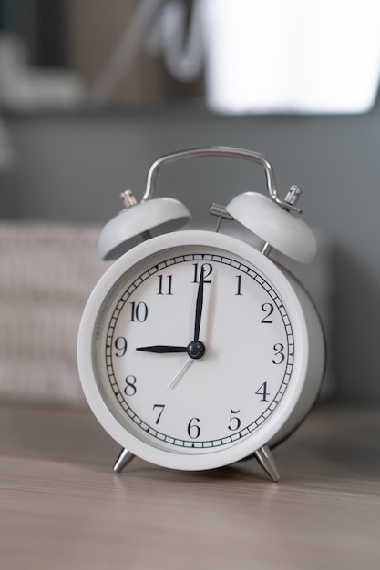 Primer plano de un reloj despertador blanco redondo en una mesa en el dormitorio