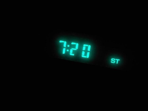 Primer plano de un reloj iluminado en un cuarto oscuro