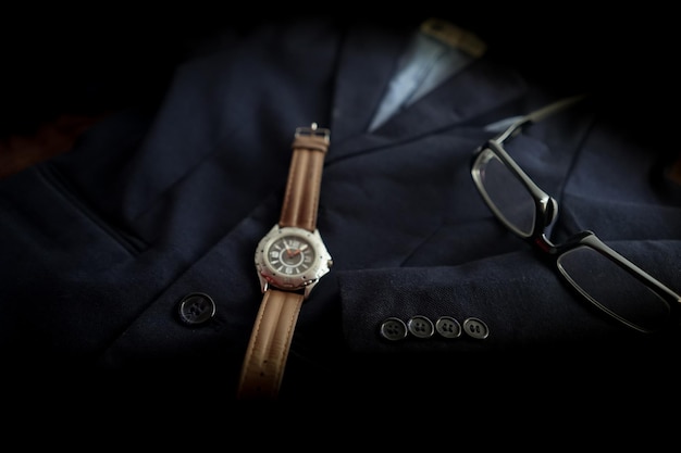 Primer plano de un reloj de pulsera con gafas en blazer