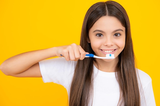 Primer plano de retrato de adolescente feliz Chica adolescente divertida se cepilla los dientes concepto saludable dental aislado sobre fondo amarillo Dientes de niños sanos Concepto de medicina oral y estomatología Chica sonriente