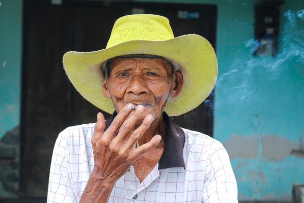 Primer plano retrato de un anciano javanés asiático con un cigarrillo en la mano