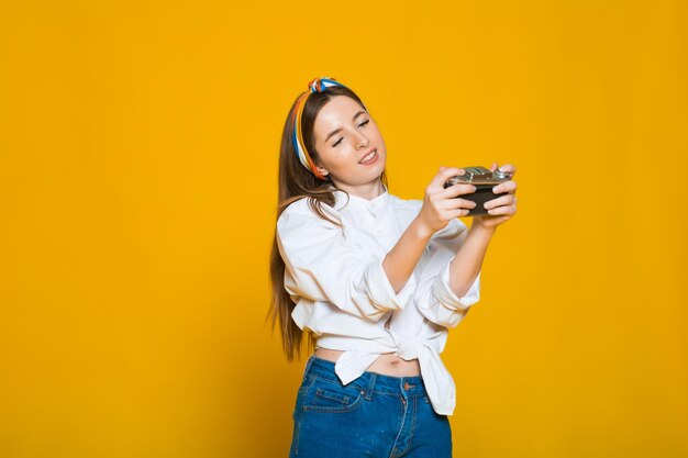 Primer plano retrato de una chica guapa sonriente vestida tomando fotos en una cámara retro aislada