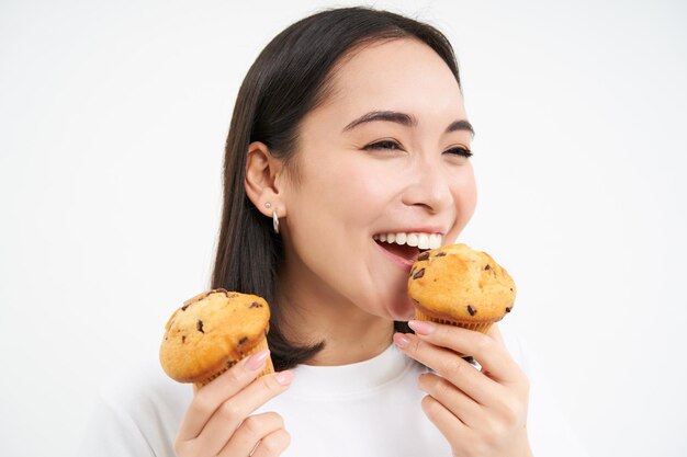 Primer plano retrato de feliz hermosa mujer sonriente comiendo pasteles cupcake le gusta panadería backgrou blanco