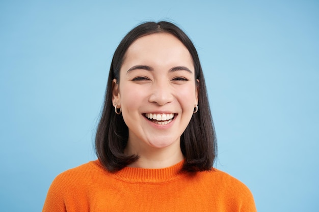 Primer plano retrato de hermosa mujer asiática riendo muestra sincera felicidad sonriendo a la cámara suplente