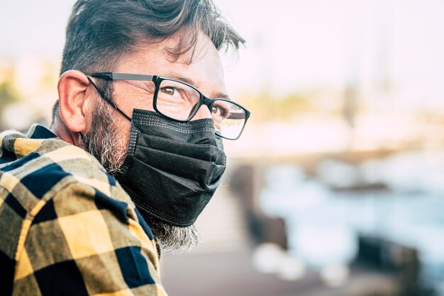 Foto primer plano retrato de un hombre guapo con mascarilla médica y glases para protegerse contra la emergencia pandémica del coronavirus covid-19: las personas y las medidas de seguridad usan máscara al aire libre